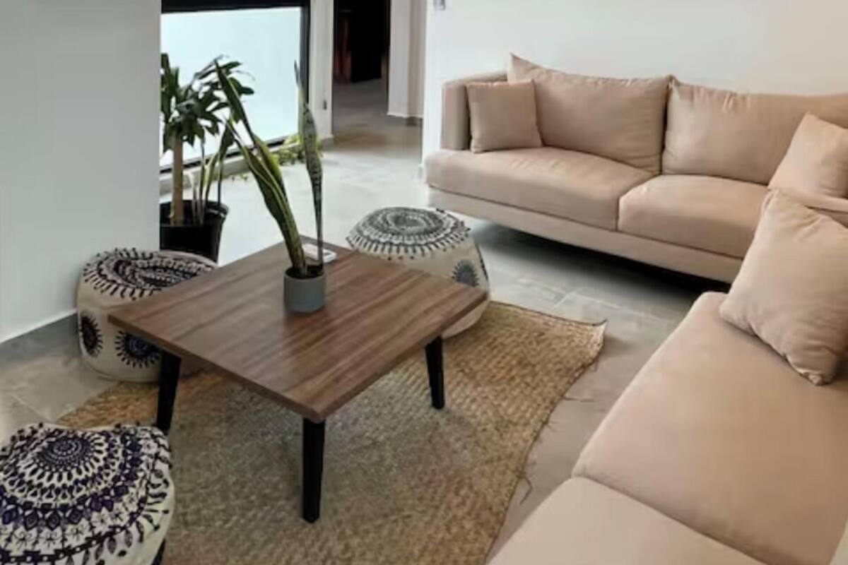 Un salon moderne avec un canapé beige, une table basse en bois et une plante en pot.