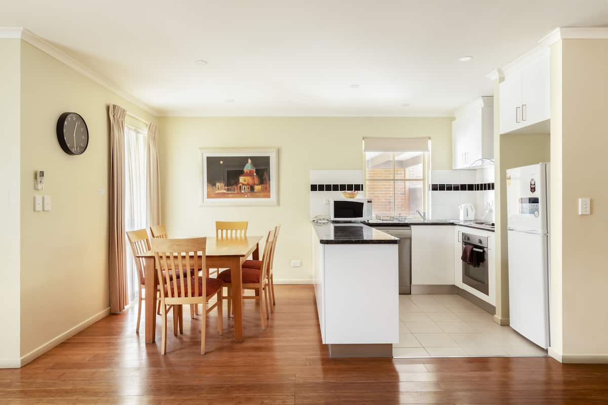 A modern kitchen with white cabinets, a wooden dining table, and a built-in island.