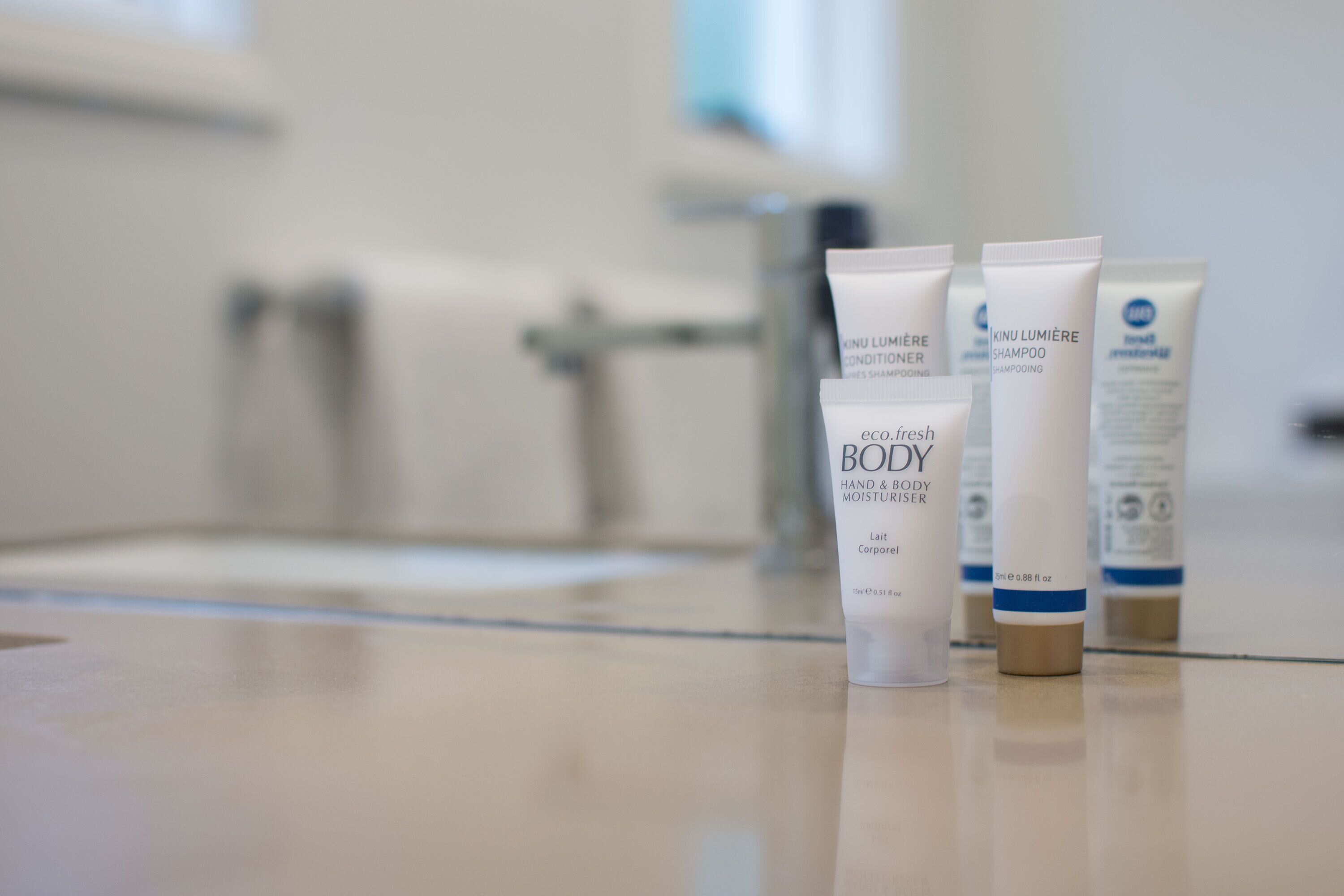 Cuatro botellas de productos de cuidado corporal sobre una encimera de baño.