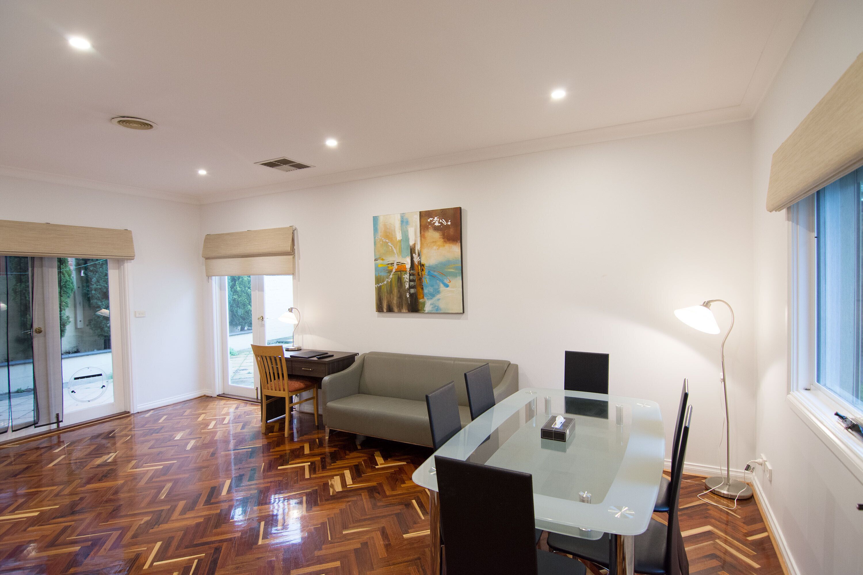 Una sala moderna con una mesa de vidrio, un sofá y un piso con patrón de espiga.