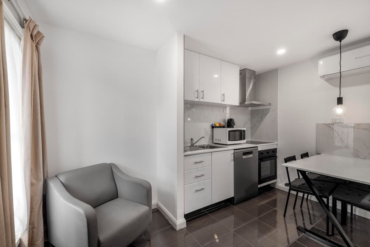 A modern kitchen with white cabinets, a microwave, a sink, and a dining area with a table and chairs.