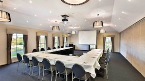 A conference room with a long table, chairs, a projector screen, and a large screen. - Buckingham Apartment (Highett)