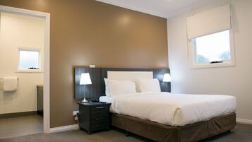A bedroom with a large bed, two bedside lamps, a nightstand, and a window with a view.
