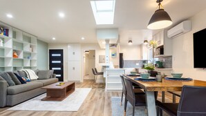 A modern living room with a sofa, coffee table, and a dining area with chairs and a table. There is a kitchen area with cabinets and a microwave. - Family-friendly Modern Cozy Downtown Mill Valley Unit in San Francisco Bay Area (Mill Valley)