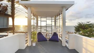 Un balcone con vista sul mare, caratterizzato da una ringhiera bianca, due cuscini blu e un tavolino.