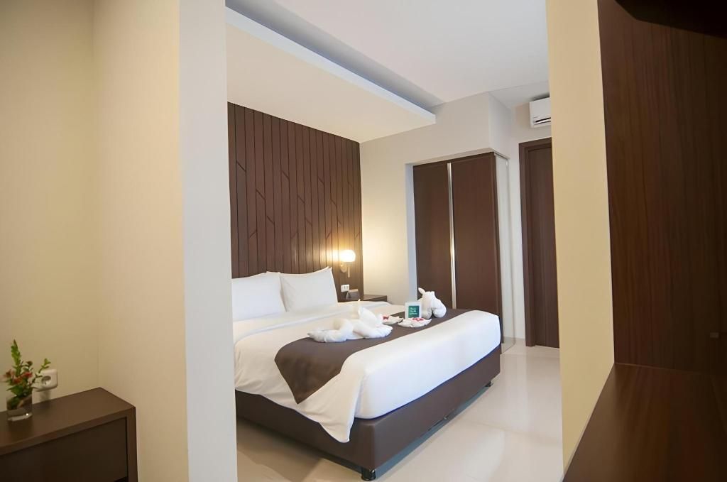 A modern hotel room with a large bed, a bedside table, and a wardrobe.
