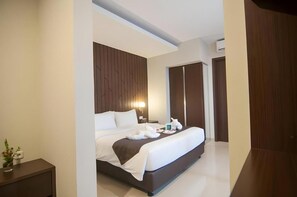 A modern hotel room with a large bed, a bedside table, and a wardrobe. - Horison Ultima Singkawang (Karimunting)