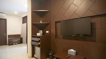 A modern living room with a flat-screen TV mounted on the wall, a built-in shelving unit, and a small table with a remote control.