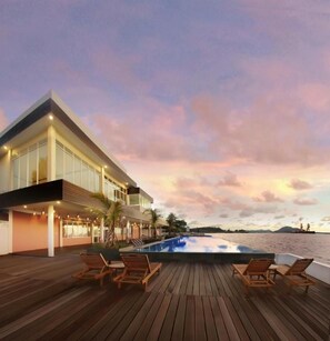 A modern building with a pool and lounge chairs.
