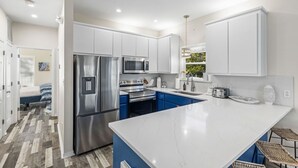 A modern kitchen with white cabinets, stainless steel appliances, and a marble countertop.