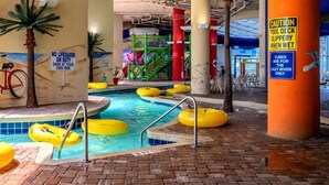 Un espace piscine intérieure doté de plusieurs couloirs, de bouées jaunes et d’un panneau indiquant la présence d’un sauveteur.