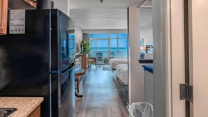 Una habitación de hotel compacta con kitchenette, un balcón con vistas y una cama.