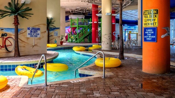 Zona de piscina interior con múltiples carriles, flotadores amarillos y un letrero de salvavidas.