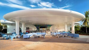 Un espace extérieur moderne, aménagé avec des meubles blancs et bleus, un bar et un mur aux couleurs vives.