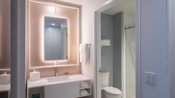 Un baño moderno con lavamanos, espejo y retrete blancos.