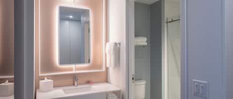 Un baño moderno con lavamanos, espejo y retrete blancos.