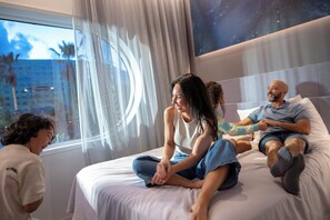 A bedroom with a bed, a window with curtains, and a wall with a starry night design.