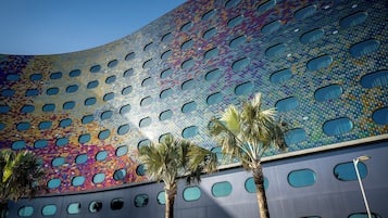 Un edificio moderno con facciata curva e motivo a mosaico, caratterizzato da numerose finestre circolari.