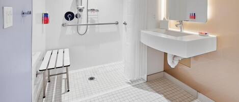 A modern bathroom with a shower, a sink, and a bench.