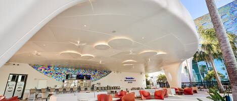 A modern lounge area with seating, a colorful wall, and a ceiling with circular lights.
