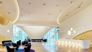 A spacious lobby with a modern design, featuring a reception desk, seating areas, and large windows providing natural light. - Universal's Terra Luna Resort (Orlando)