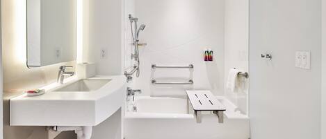 A modern bathroom with a sink, mirror, and bathtub.