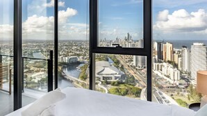Ein Hotelzimmer in einem Hochhaus mit großem Fenster und Blick auf die Stadt, einschließlich eines Flusses und eines Stadions.