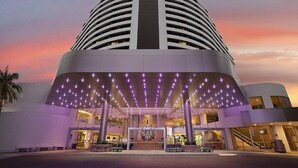 Ein modernes Hotel mit einem markanten Sternenlogo, einer geschwungenen Fassade und einem überdachten Eingangsbereich mit violetter Beleuchtung.