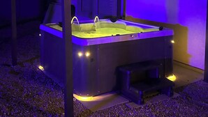 Un jacuzzi con dosel, rodeado de grava, bajo una edificación con techo inclinado.