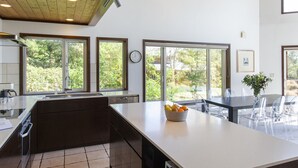 A modern kitchen with large windows, a central island, and a dining area with clear chairs. - Casa La Mount by Elite Havens (Niseko)
