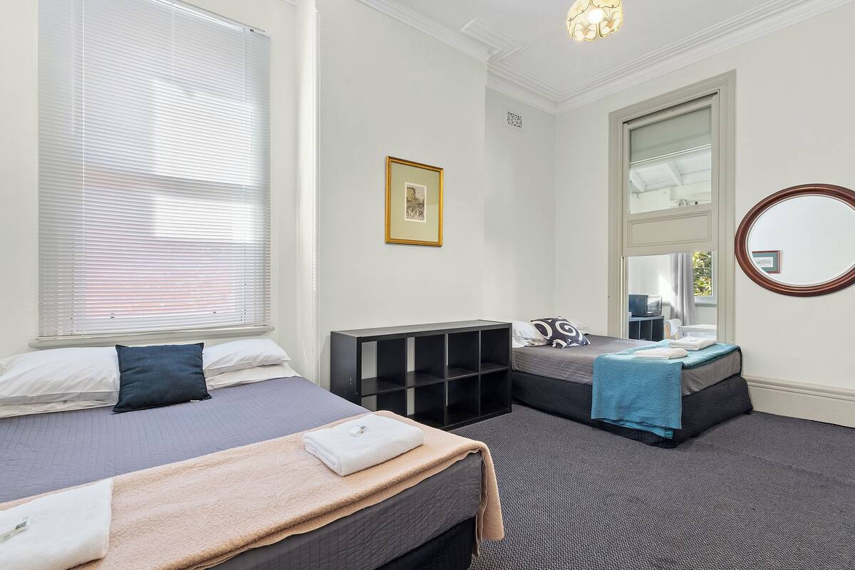 Ein Hotelzimmer mit zwei Betten, einem Kleiderschrank, einem Spiegel und einem gerahmten Bild an der Wand.