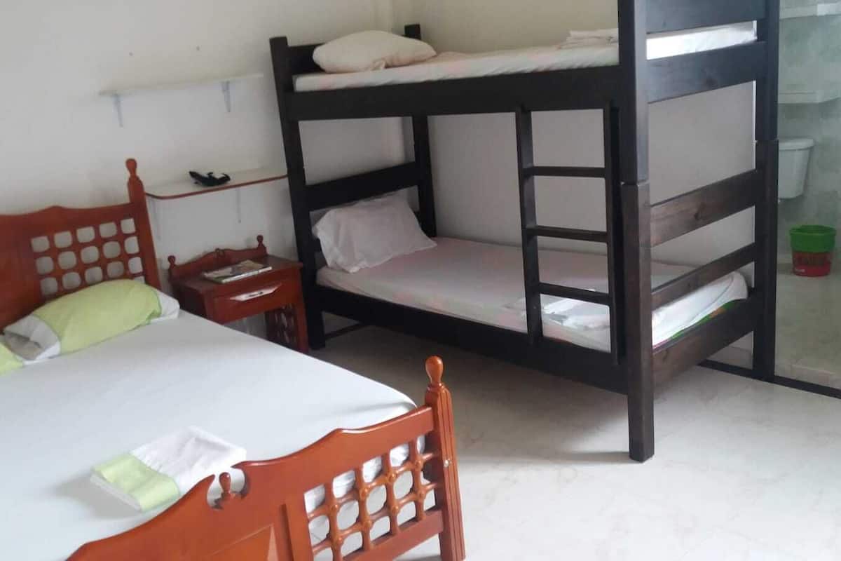 A room with a single bed, a wooden bunk bed, a nightstand, and a small table.