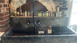 Una cocina rústica con un arco de piedra, armarios de madera y una encimera negra.