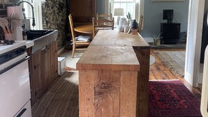 Una cocina rústica con isla de madera, pared de piedra y vigas a la vista.