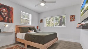 A bedroom with a wooden bed, two windows, a ceiling fan, and a colorful rug. - Sunset Serenity: Your Fort Lauderdale Retreat (Fort Lauderdale)