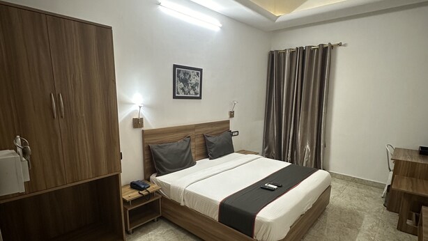 Quarto com cama, guarda-roupa de madeira, mesa de cabeceira e ventoinha no teto.