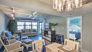 A spacious living room with a dining area, a television, and a bedroom visible through an open door. - Beachfront on no-drive beach.  Park & walk to local spots.   (New Smyrna Beach)