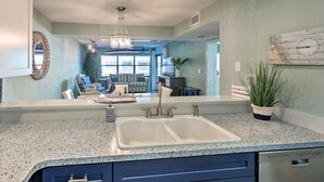 A kitchen with a large island, a double sink, and a chandelier. - Beachfront on no-drive beach.  Park & walk to local spots.   (New Smyrna Beach)