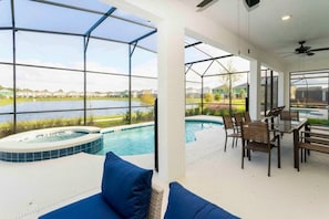 A pool area with a hot tub, outdoor seating, and a view of a lake. - 10BD Bella Vida Beautiful Home Near Parks (BV 303) (Kissimmee)