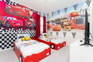 A bedroom with two beds, a large wall mural of animated cars, and a checkered pattern on the walls. - 10BD Bella Vida Beautiful Home Near Parks (BV 303) (Kissimmee)