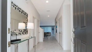 A hallway with a glass partition, a mirror, two lamps, and a door. - 10BD Bella Vida Modern Home Private Pool (BV 4456) (Kissimmee)