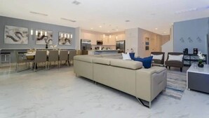 A modern living room with a sofa, dining area, kitchen, and artwork on the walls. - 10BD Bella Vida Modern Home Private Pool (BV 4456) (Kissimmee)