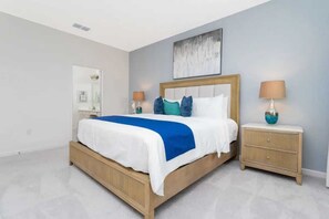A modern bedroom with a bed, bedside tables, and a wall-mounted artwork.
