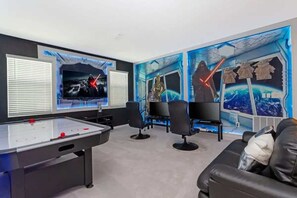 A room with a foosball table, a couch, and Star Wars-themed wall art.