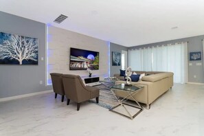 A modern living room with a sofa, chairs, a coffee table, and artwork on the walls.
