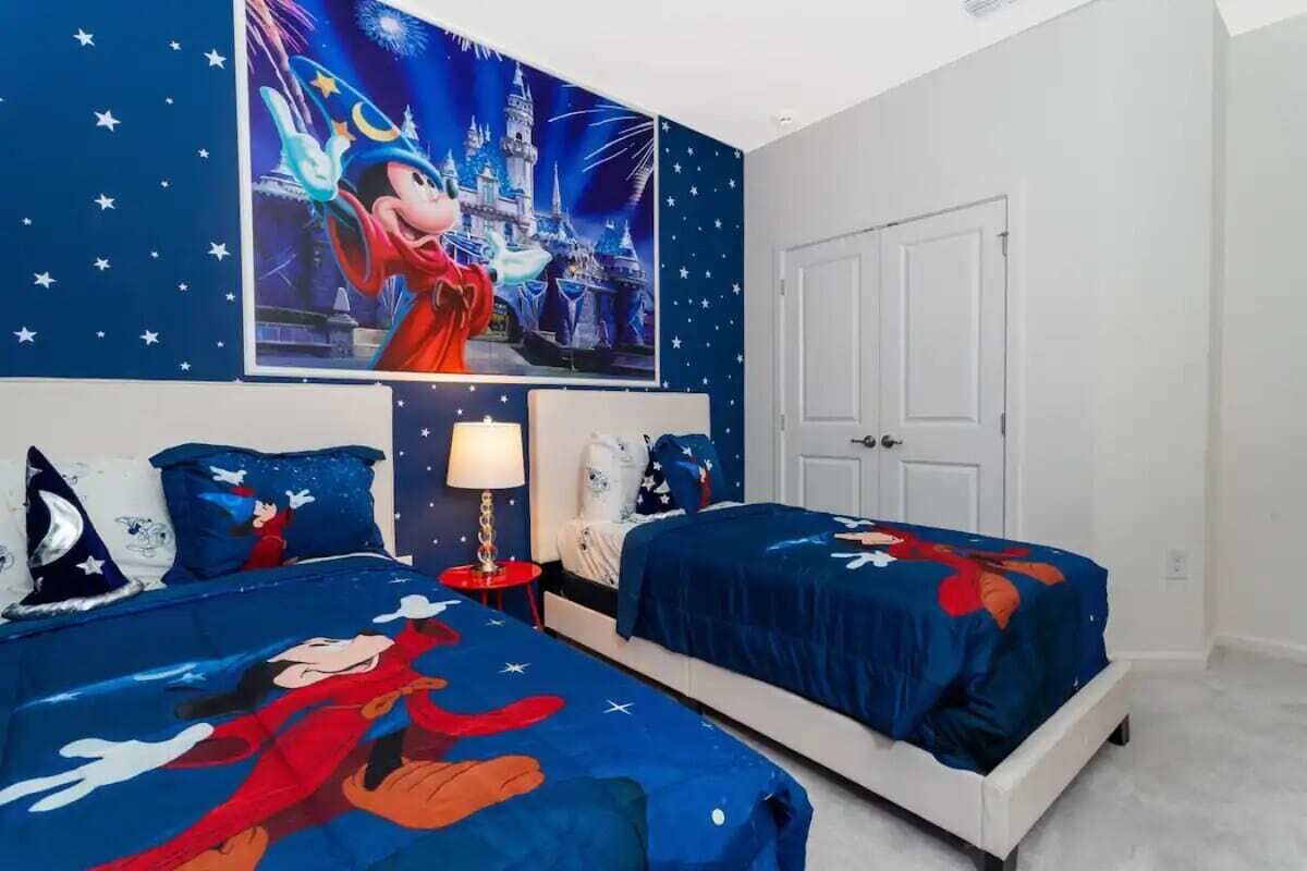 Makuuhuoneessa on kaksi sänkyä, yöpöytä, lamppu ja suuri seinäjuliste, jonka aiheena on Disney.