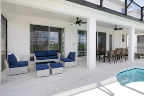 Eine moderne Terrassenanlage im Freien mit weißen Möbeln, einem Pool und Deckenventilatoren.