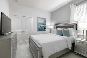 Ein Schlafzimmer mit einem Bett, Nachttischen, einem Fernseher, einem Kleiderschrank und einem Bild an der Wand.