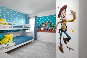 Quarto de criança com beliches, um mural na parede e um pôster do Woody.