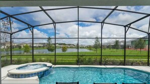 Ein Pool mit Whirlpool, umgeben von einer überdachten Terrasse mit Blick auf einen See und Häuser.